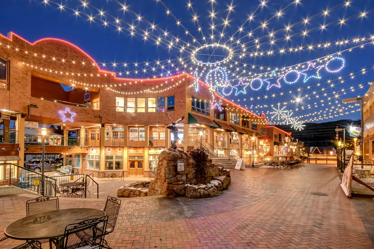 A lively exterior scene of string lights, decorative stars, a rock fountain, and charming shopfronts, perfect for evening strolls or holiday celebrations. The atmosphere is festive, intimate, and magical, echoing the romantic ambiance described in the section.