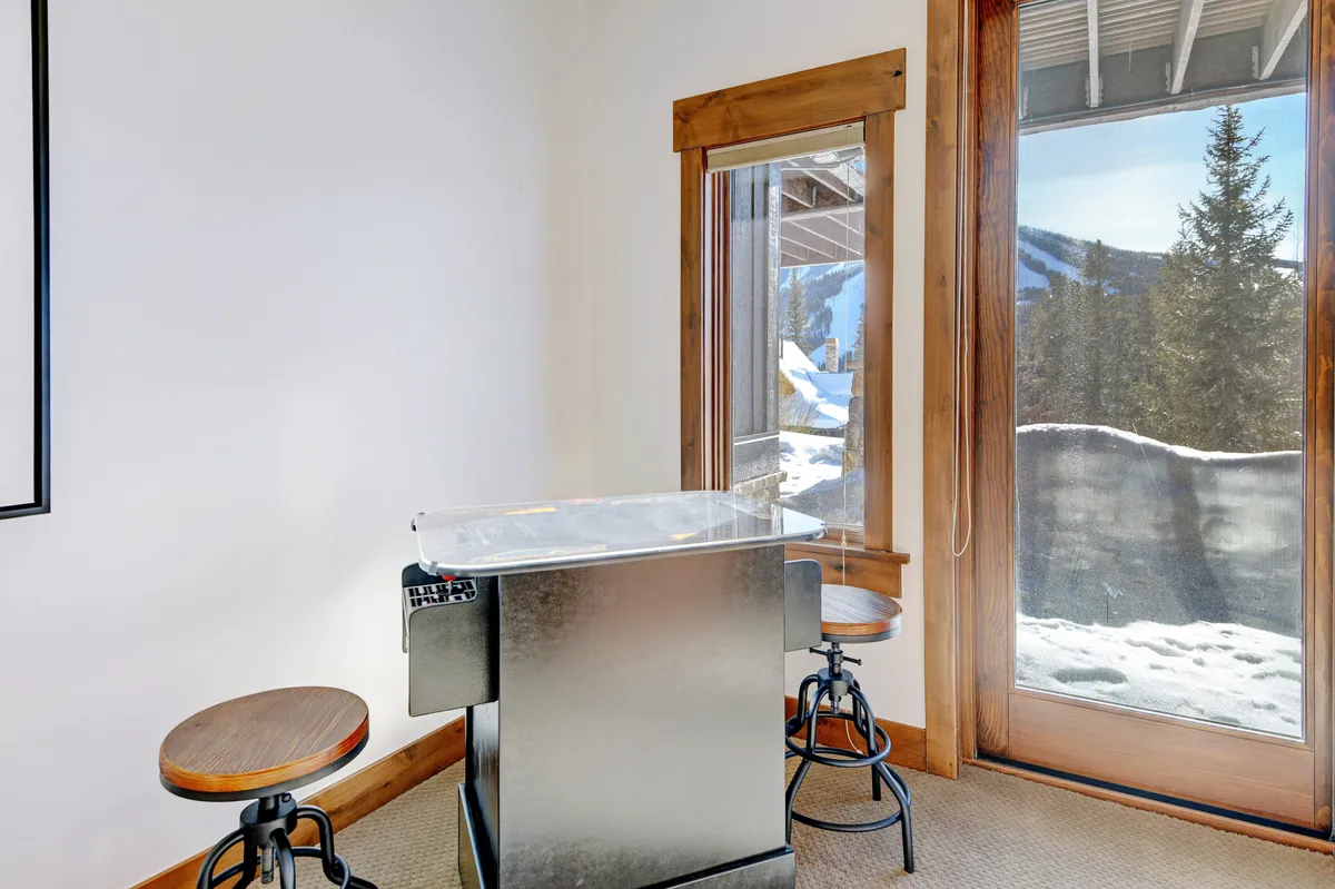 A stylish bar area with a large window framing a breathtaking mountain view. The setting suggests a perfect spot for evening cocktails or leisurely drinks while enjoying the scenery, with a relaxed, inviting atmosphere.