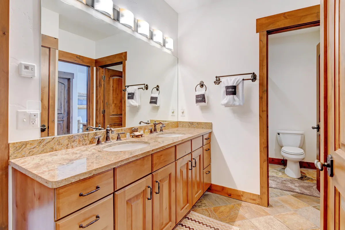 A bright bathroom featuring a double sink vanity, large mirrors, modern light fixtures, and calming tones. The setup is perfect for shared routines and ensures convenience for multiple guests or family members.